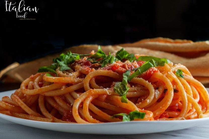 A plate of Bucatini all'Amatriciana garnished with grated Pecorino Romano cheese.