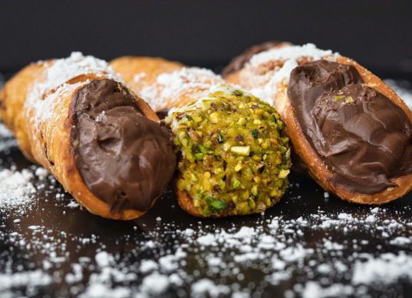 A plate of traditional Italian cannoli filled with creamy ricotta and dusted with powdered sugar.