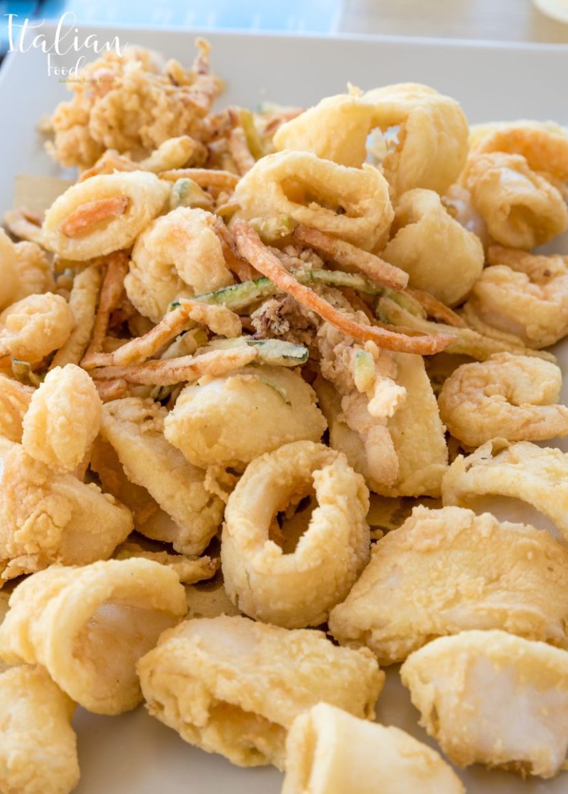 A plate of traditional Fritto Misto with fried calamari, shrimp, and small fish.